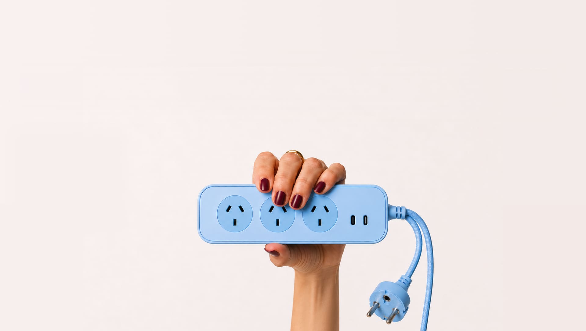 Person holding the baby blue Roamboard powerboard with its braided cord and European plug